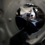 Palestinians inspect a car hit in an Israeli strike on