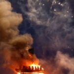 Bonfire burns with effigy of migrants in a boat atop