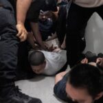 A migrant is detained by federal immigration officers at U.S.