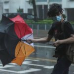 A man struggles with an umbrella while walking against strong