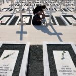 Relatives sit next to the graves of soldiers killed in