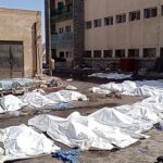 Bags containing bodies lie on the ground at Sweida National
