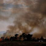 FILE PHOTO: A wildfire burns next to a house on