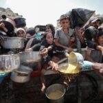 Palestinians wait to receive food from a charity kitchen, in