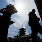 Visitors exposed to the sun walk at the Sensoji temple