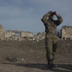 An ethnic Armenian soldier looks through binoculars as he stands