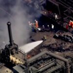 Firefighters spray water on the site of an explosion at