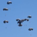 Aid packages dropped from an airplane descend over Gaza, as