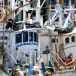 A crew member works on a fishing boat, as Typhoon