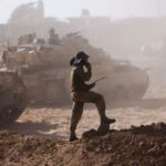 An Israeli soldier stands next to military vehicles as seen