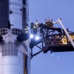 Technicians work from a lift bucket before sunrise as preparations