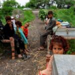 A family with their belongings takes refuge along a road
