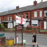 A man walks past a flag bearing the colours of