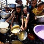 Palestinians wait to receive food from a charity kitchen, in