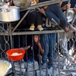 Palestinians wait to receive food from a charity kitchen, in