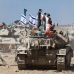 Israeli soldiers stand on a tank near the Israel-Gaza border,