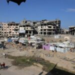 Displaced Palestinians live in tents near destroyed buildings as they