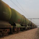 A boy walks past an oil tanker train stationed at