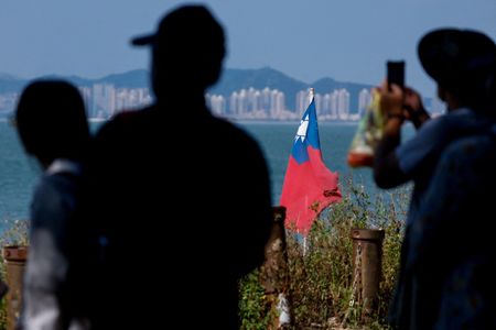 FILE PHOTO: Tourists take photos as a Taiwan flag flies,
