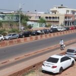 A person walks past cars parked on the roadside, amid