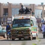 People ride on top of a minibus, amid ongoing fuel