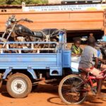 A boy on a bicycle speaks to another boy standing