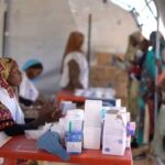 Displaced Sudanese gather and sit in makeshift tents after fleeing