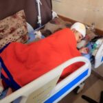 A Palestinian boy lies on a bed as he receives