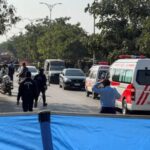 Police officers and ambulances on road cordoned off after a
