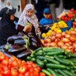 Palestinians buy vegetables at a market in Nuseirat