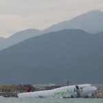 A cargo plane lies partially in the sea after veering