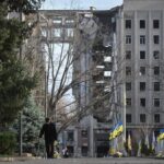 A man walks next to a damaged building in Mykolaiv