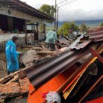 Residents walk on rubble in front of a restaurant in