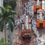 Police officers wearing protective suits walk near the site of