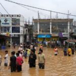 People gather at an area affected by floods, following heavy