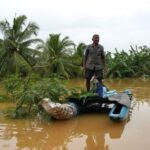 A man stands on a boat at an area affected