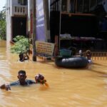 People wade through a flooded street, following Cyclone Ditwah in