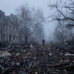 Ukrainian serviceman walks near apartment buildings damaged by Russian military