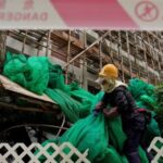 Worker removes scaffolding mesh from a building at Sui Wo