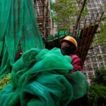 Worker removes scaffolding mesh from a building at Sui Wo