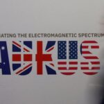 A man walks past an AUKUS sign at the Indo