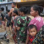 Survivors queue to collect relief supplies in an area affected