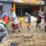 Survivors queue to collect relief supplies in an area affected