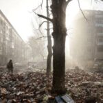 FILE PHOTO: Ukrainian serviceman walks near apartment buildings damaged by