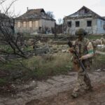 Ukrainian serviceman walks near buildings damaged by Russian military strike