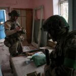 Ukrainian servicemen eat inside of a building damaged by Russian