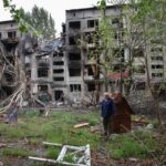 A resident stands near buildings damaged by Russian military strikes