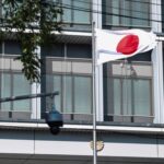 Japan’s national flag flutters next to a surveillance camera at