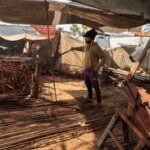 Palestinian worker reshapes and straightens steel bars recovered from destroyed