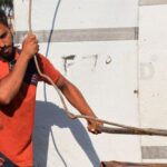 Palestinian worker reshapes and straightens steel bars recovered from destroyed